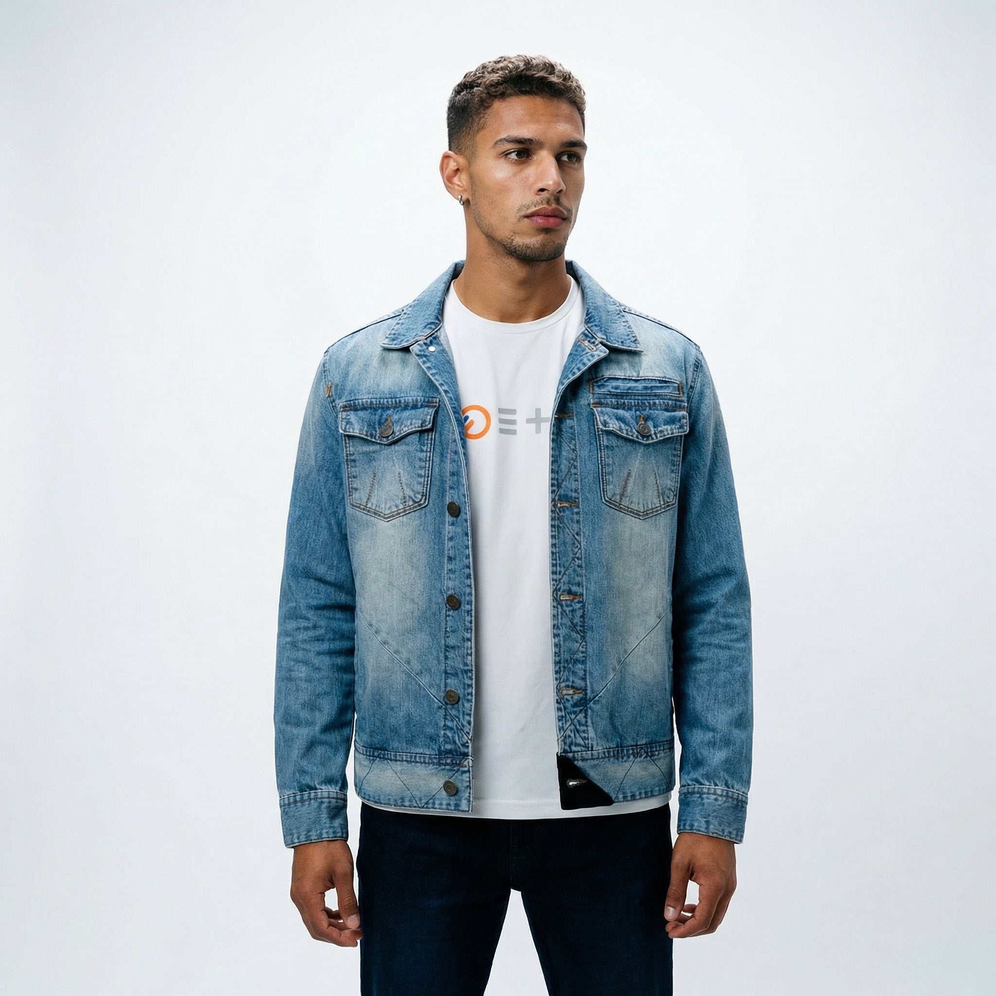 A male model styling the ETRN engineered light blue denim jacket over a white graphic t-shirt and dark blue jeans for an edgy, premium streetwear look.
