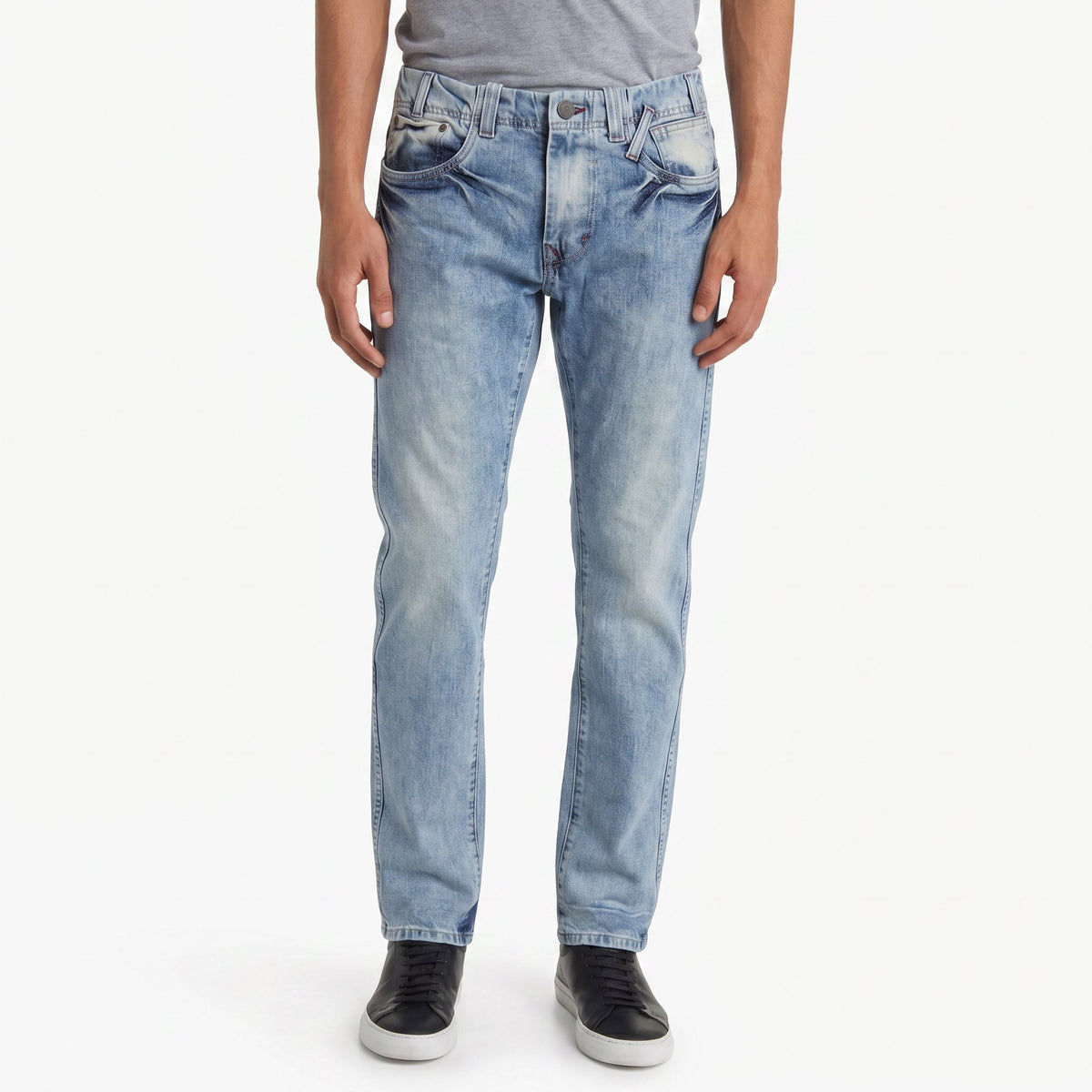 A model wearing light-wash blue ETRN denim jeans with a faded wash, paired with a gray t-shirt and black sneakers, shown from the waist down.