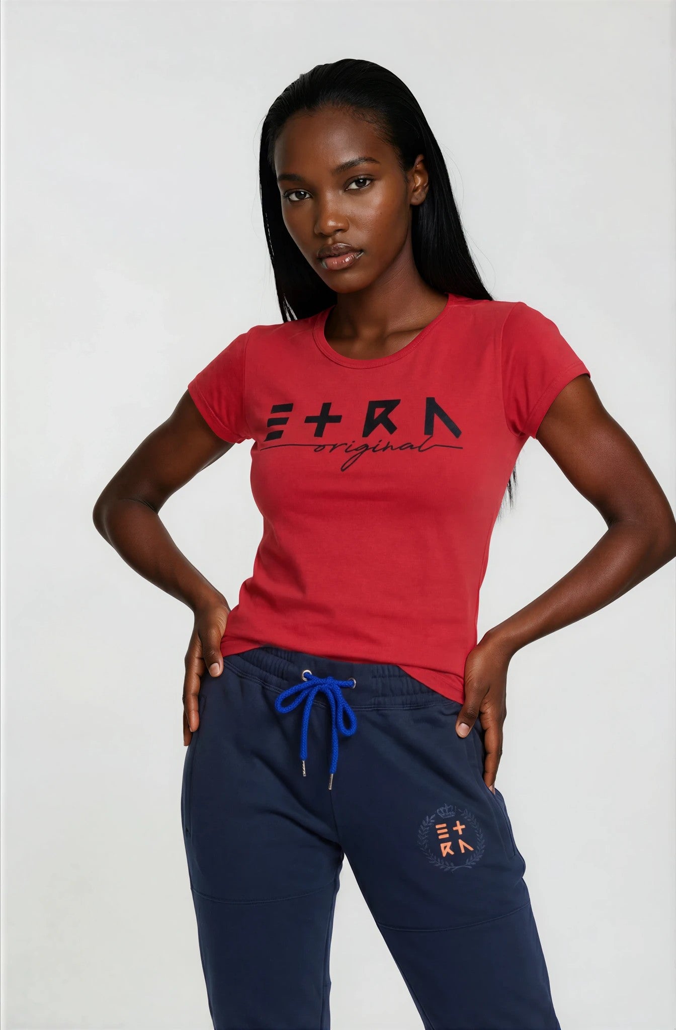 Woman wearing a red t-shirt with 'ETRN' logo and navy pants