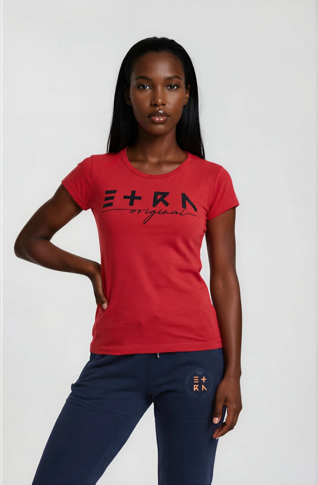 Woman wearing a red ETRN Original t-shirt with branding and navy pants